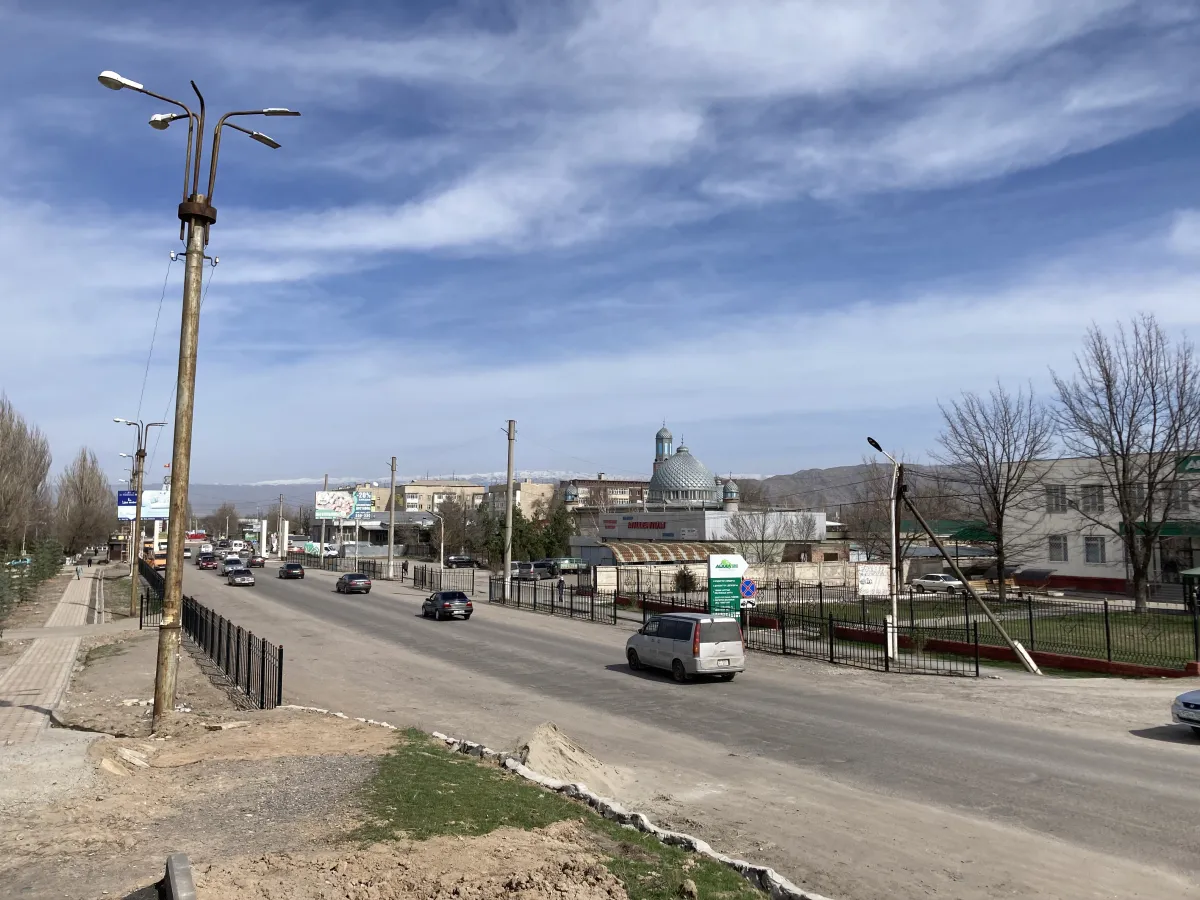 Городская улица Токмока с движением и мечетью на фоне гор