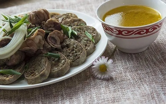 Rondelles de byzhy servies avec de l’oignon, des abats et un petit bol de bouillon