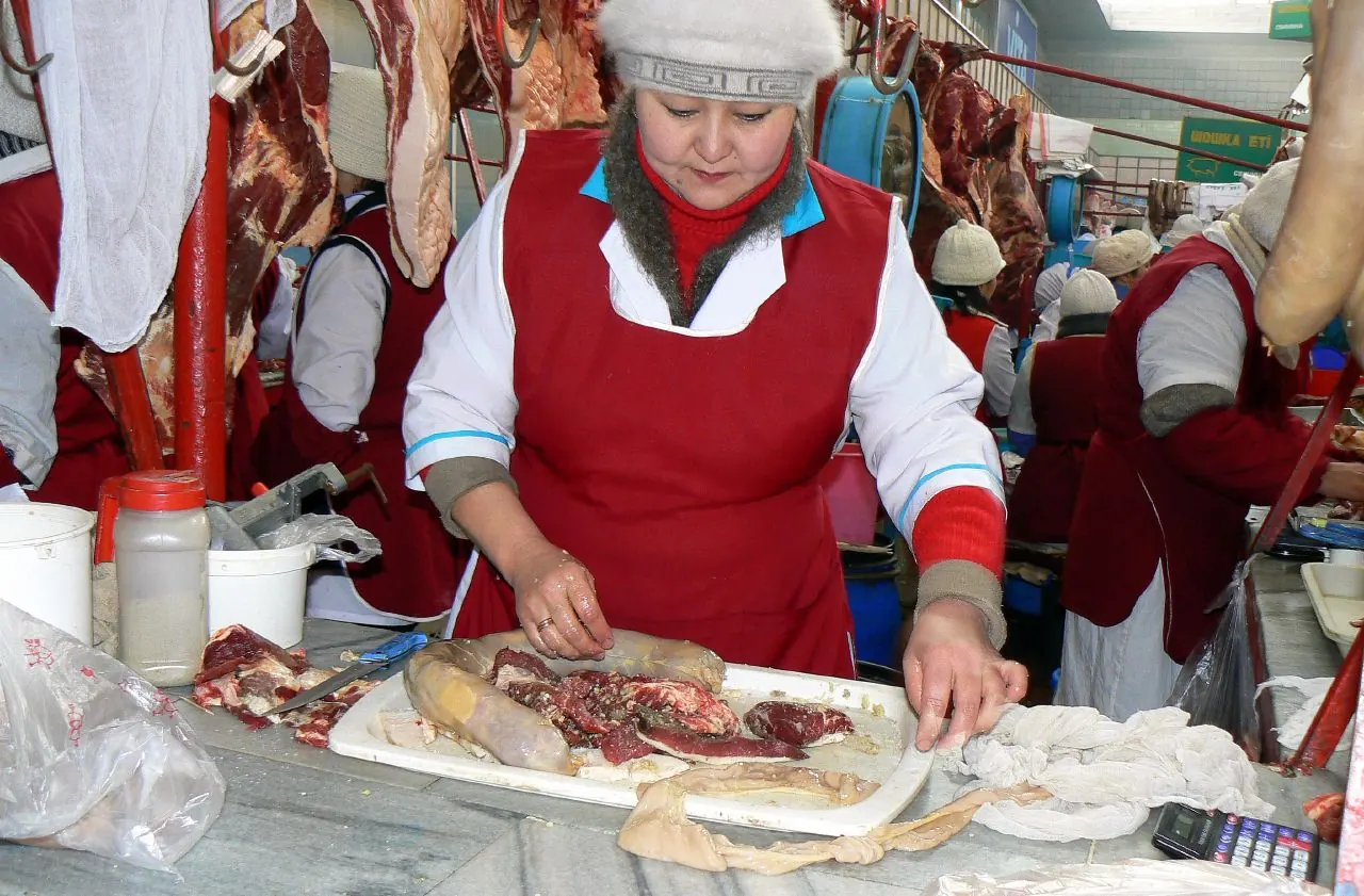 Un vendeur introduit à la main des bandes de viande et de graisse de cheval dans un boyau
