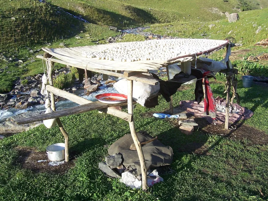 Grande claie de séchage chargée de kurut au-dessus d’un torrent de montagne au Kirghizstan