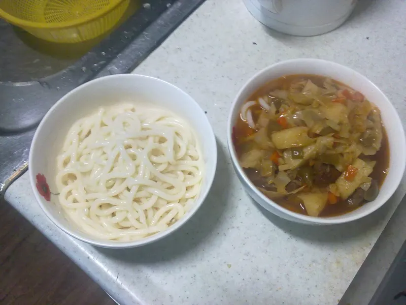 Nouilles de laghman bouillies et sauce à la viande et aux légumes dans deux bols séparés