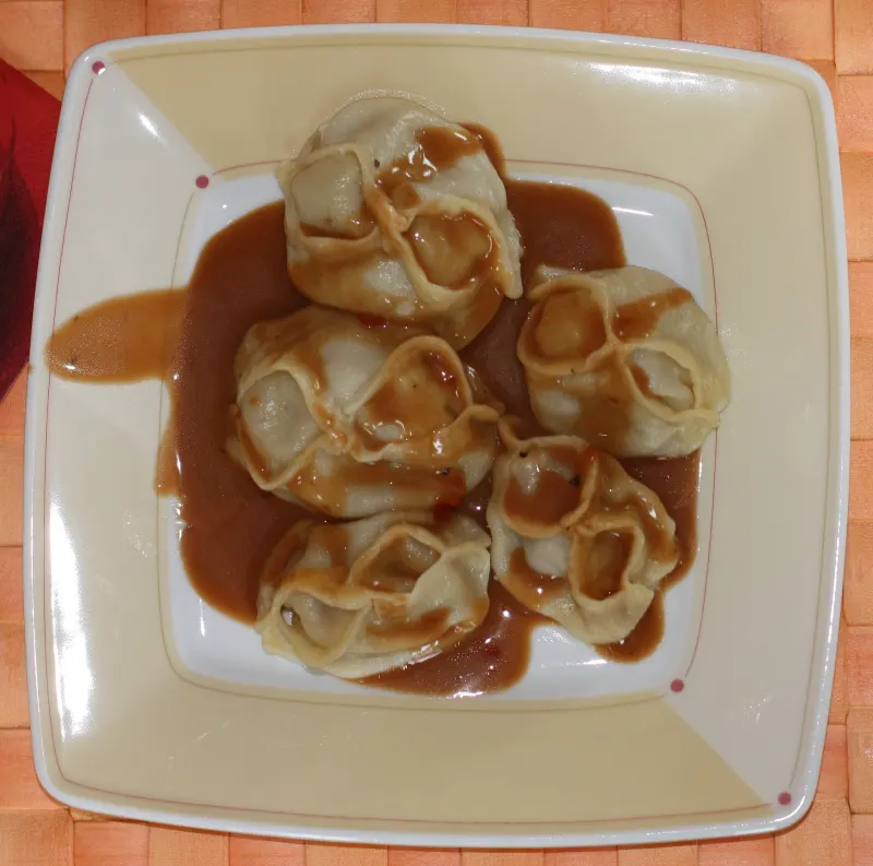 Des manty maison sont présentés avec une sauce pimentée rouge
