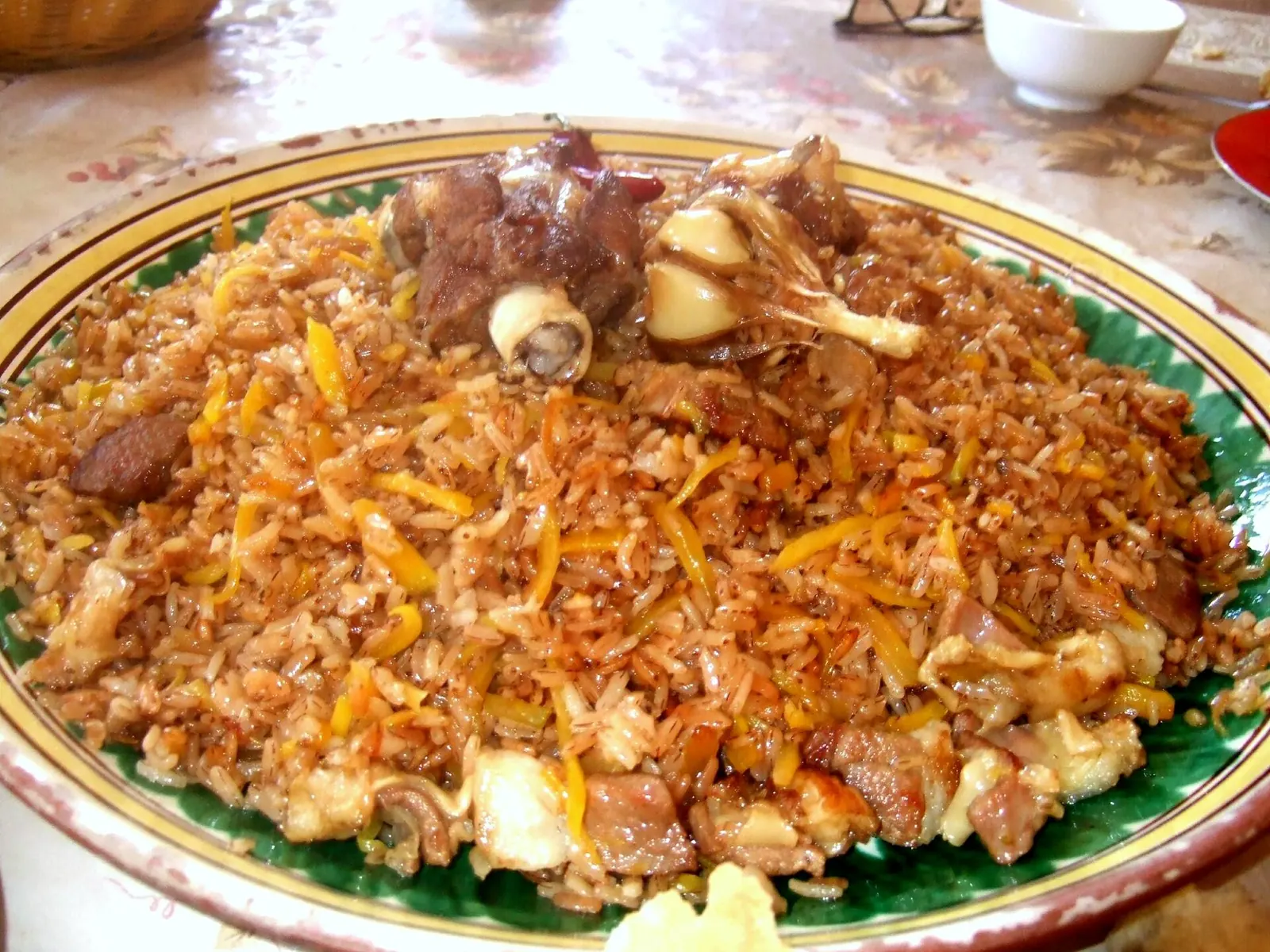 Плов с рисом, морковью, мясом и чесноком на большом блюде