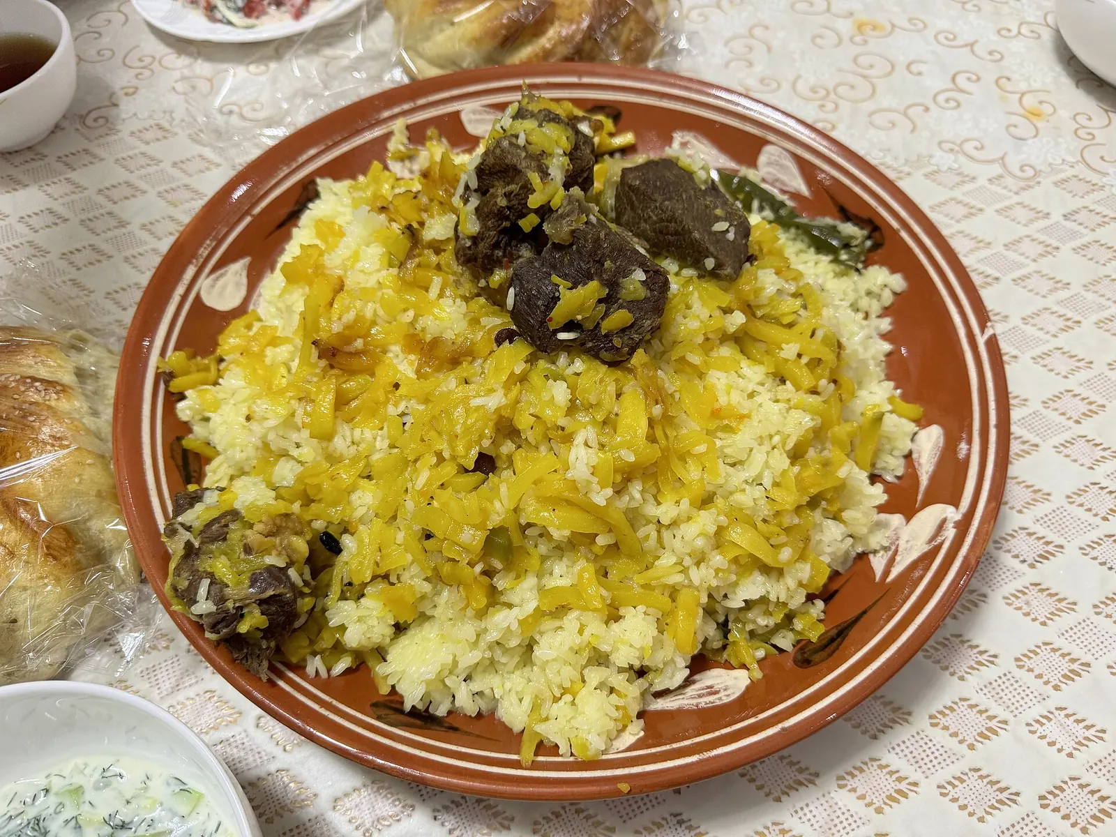 Домашний палов с рисом, морковью и крупными кусками мяса на большом блюде