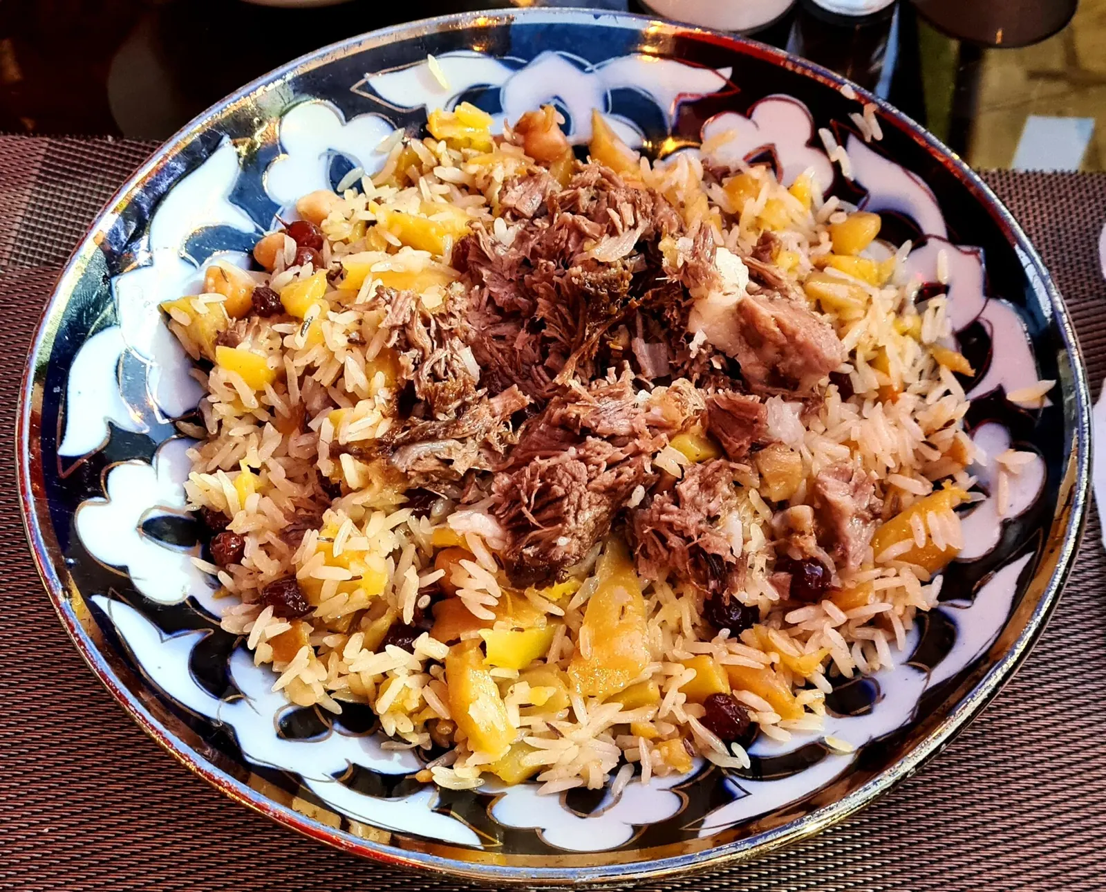 Плов с рисом, морковью, барбарисом и мясом на узорном блюде