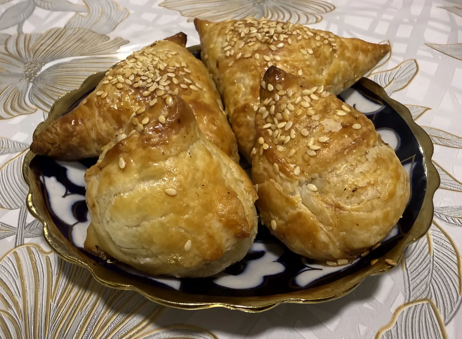 Четыре домашние самсы с кунжутом лежат на узорной тарелке