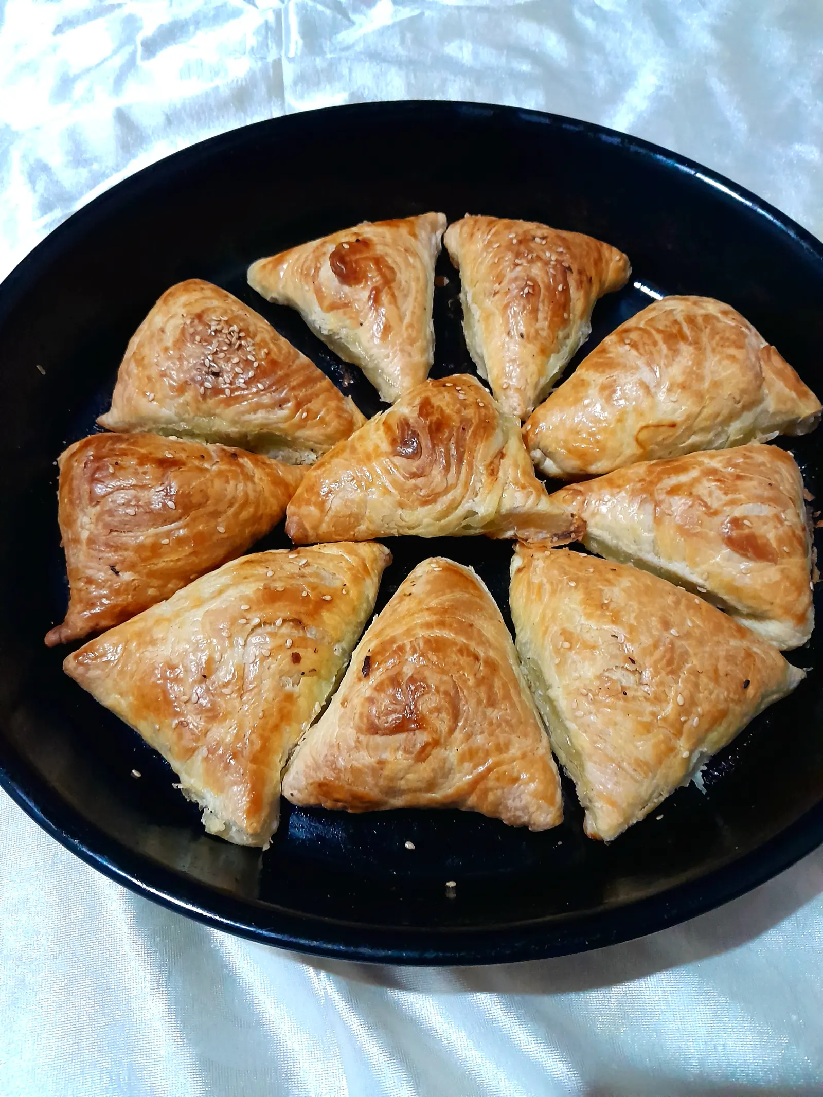 Слоёные треугольные самсы уложены кругом в чёрной форме