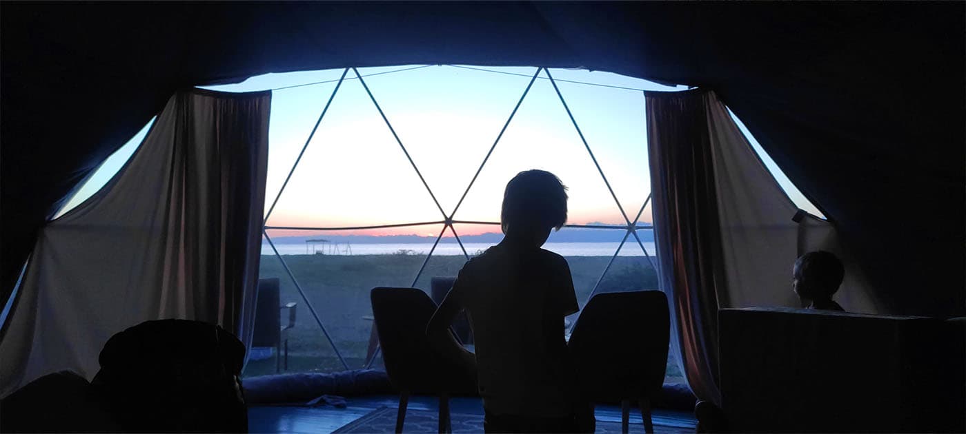 Panoramik penceresinden göl görünen kubbeli glamping iç mekânı