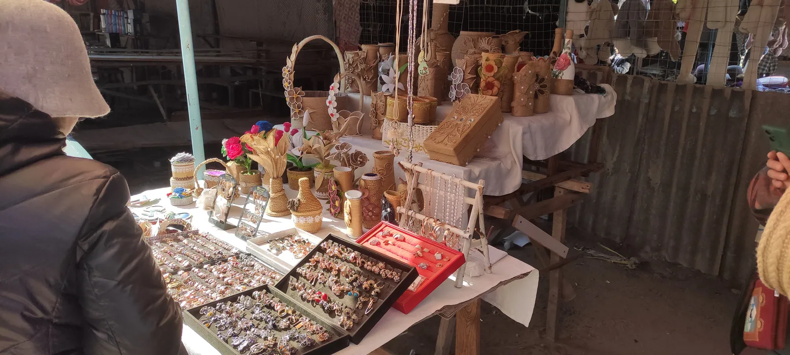 Bijoux, objets tressés et petits souvenirs présentés sur un étal du marché de Bosteri