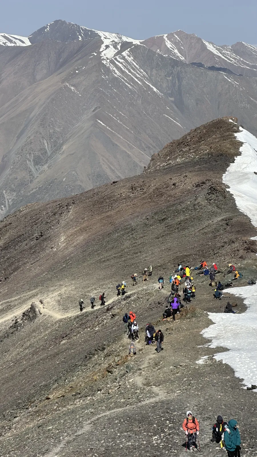 Participants montant sur un versant d’éboulis et de neige