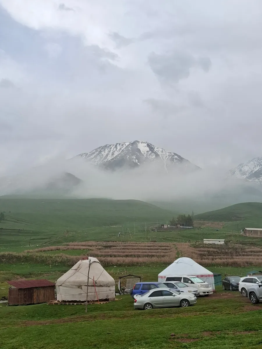 Yourtes, vallée verte et versants enneigés de Chunkurchak dans le brouillard