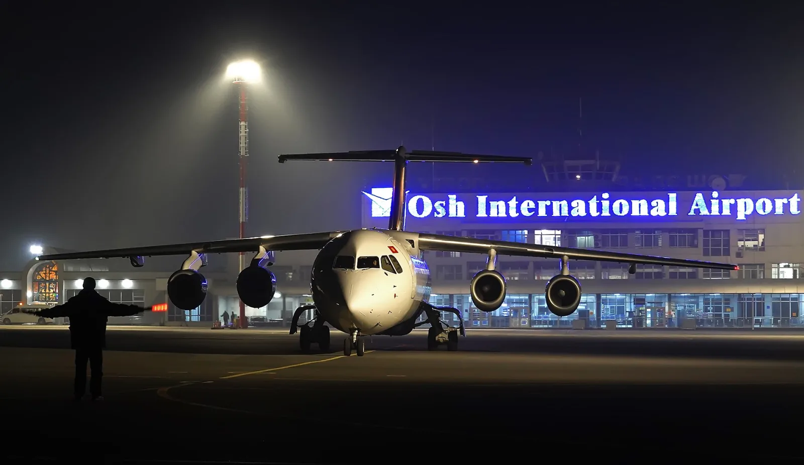 Освещённый терминал аэропорта Ош и самолёт на рулёжной дорожке ночью